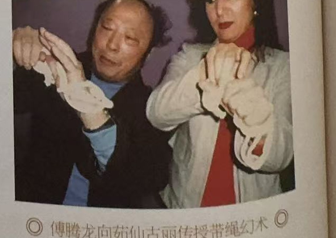 傅腾龙与茹仙古丽各戴白手套,面对面比划一根绳的手法
